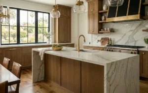 Blogs 12 A luxury white kitchen remodel comparing a farmhouse sink vs undermount sink, featuring custom Shaker cabinets, premium white quartz countertops with bold gray veining, and a hammered copper farmhouse apron-front sink beneath a large window. The open-concept design includes an elegant kitchen island in the foreground and a couple reviewing architectural plans under warm pendant lighting